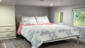A bedroom with a bed, a nightstand, a wardrobe, and a window. - NEW! The Gilded Grove Cottage in Charming Guerneville (Guerneville)