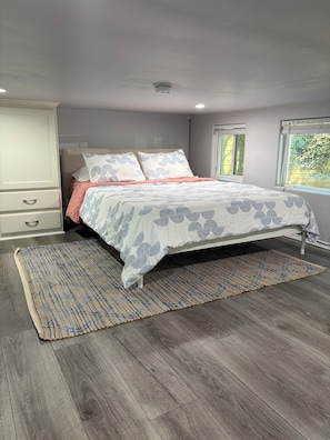 A bedroom with a bed, a nightstand, a wardrobe, and a window.