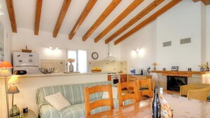 A kitchen with wooden beams, a dining area with chairs, a sofa, and a fireplace. - Piatonu - SOLLACARO - Gîte (SOLLACARO)