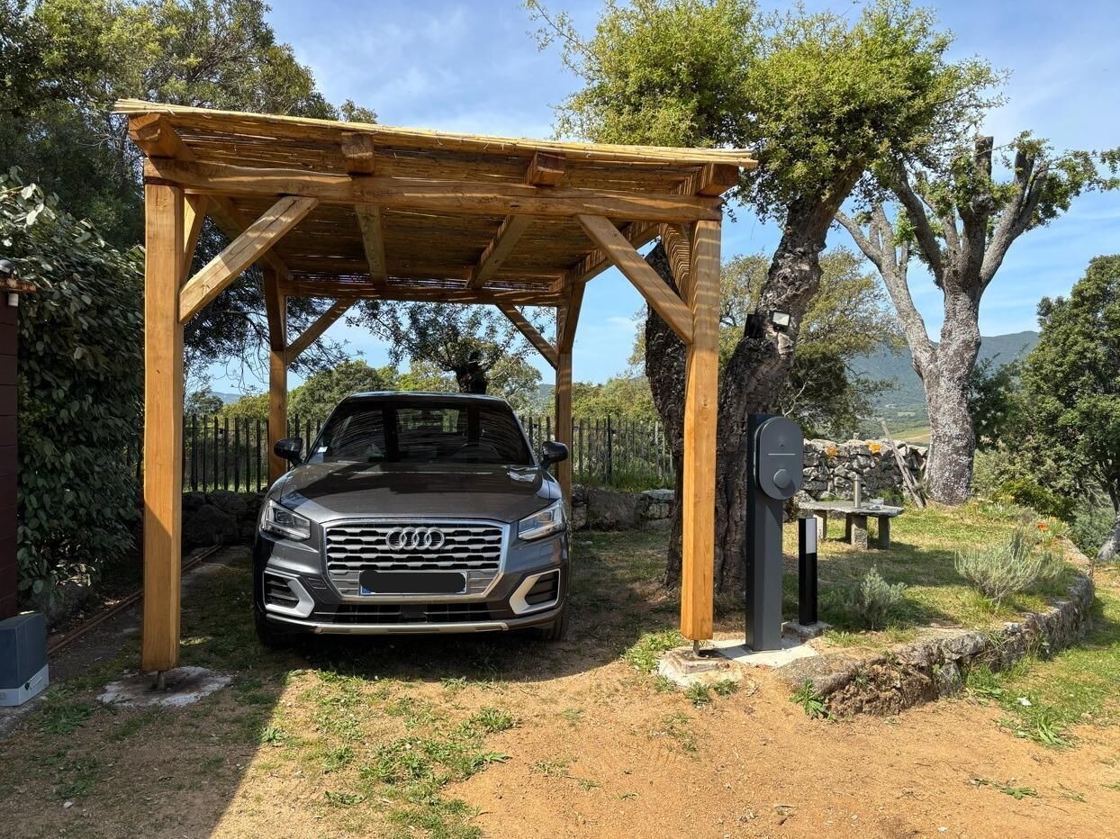 Een auto geparkeerd onder een houten pergola in een tuin.