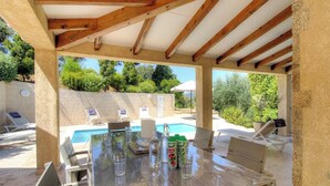 An outdoor pool area with a covered patio, lounge chairs, and a table set for dining. - Piatonu - SOLLACARO - Gîte (SOLLACARO)