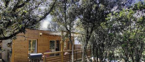 Une cabane en bois dotée d’une terrasse, entourée d’arbres.