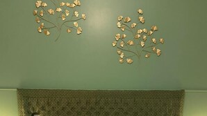 A bed with floral bedding, a textured green headboard, and two wall-mounted decorative branches. - Jeannette's welcome (PILA CANALE)