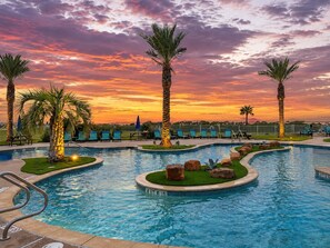Ein Swimmingpool mit Palmen, Liegestühlen und einem Sonnenuntergangshimmel.