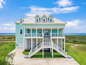 Ein zweistöckiges Haus mit Balkon und überdachter Veranda in Strandnähe.