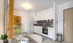 A modern kitchen with white cabinets, a built-in oven, and a stainless steel trash can. - L'albert 1er - AJACCIO (AJACCIO)