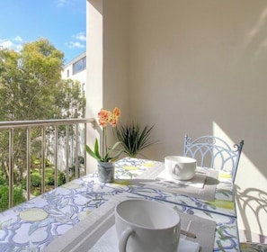 A balcony with a table set for two, a potted plant, and a chair. - L'albert 1er - AJACCIO (AJACCIO)