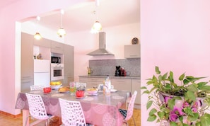 A dining area with a table set for four, a kitchen in the background, and a potted plant on the right. - Villa Monlabeur 2 - AJACCIO (AJACCIO)