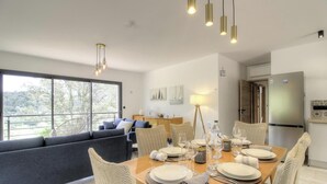 Een moderne eetruimte met een tafel gedekt voor vier personen, een bank en een koelkast op de achtergrond.
