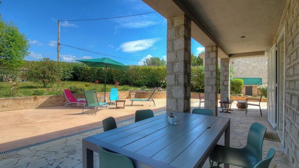 An outdoor patio with a table and chairs, a green umbrella, and a view of a garden. - Tarri-Vecchi - PORTO VECCHIO (PORTO VECCHIO)