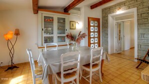 A dining area with a table set for four, white chairs, a vase with pampas grass, and a wooden ceiling. - Tarri-Vecchi - PORTO VECCHIO (PORTO VECCHIO)