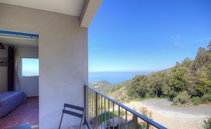 A balcony with a view of the sea and hills, a chair, and a bed. - Clelia - FARINOLE - Gîte (FARINOLE)
