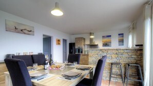 Uma sala de jantar com uma mesa comprida, cadeiras e uma parede de pedra.