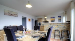 A dining area with a long table, chairs, and a stone wall. - Clelia - FARINOLE - Gîte (FARINOLE)