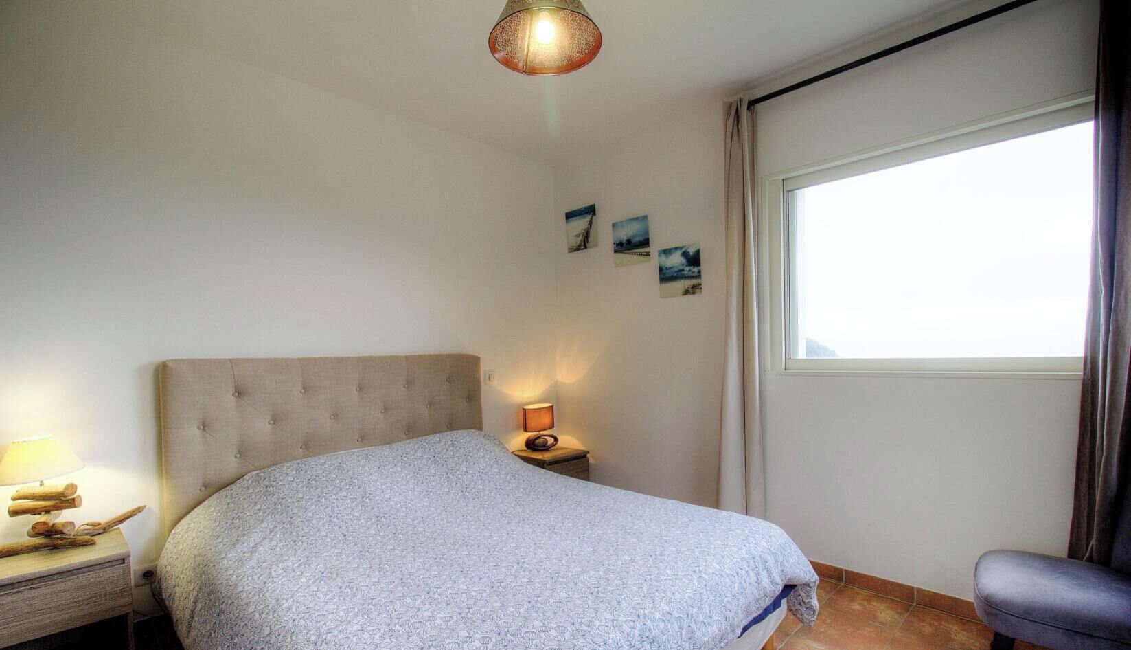 Une chambre à coucher avec un lit, une lampe de chevet et une fenêtre.