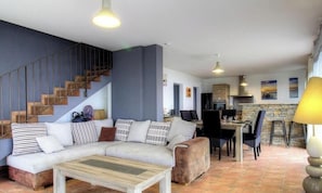 A living room with a sofa, coffee table, and a staircase. - Clelia - FARINOLE - Gîte (FARINOLE)