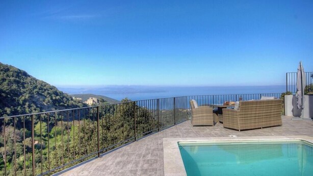 Área da piscina com vista para o mar e colinas.