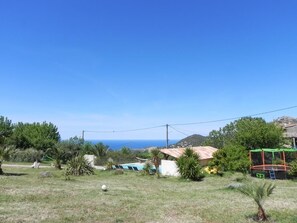 A grassy outdoor area with a pool, a small building, and a trampoline. - LE CERISIER - CATERI (CATERI)