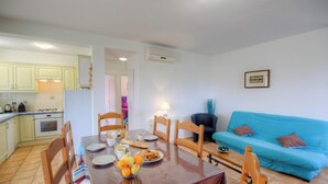 Un ambiente compatto con angolo ristoro, cucina e divano blu.
