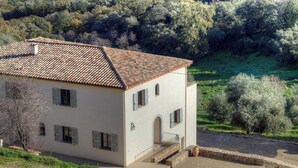 Ein zweistöckiges Haus mit einem Ziegeldach, einer kleinen Veranda und einer Steintreppe, die zum Eingang führt.