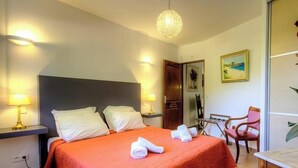 Ett hotellrum med en säng, sänglampor, ett skrivbord, en stol och en tavla på väggen.