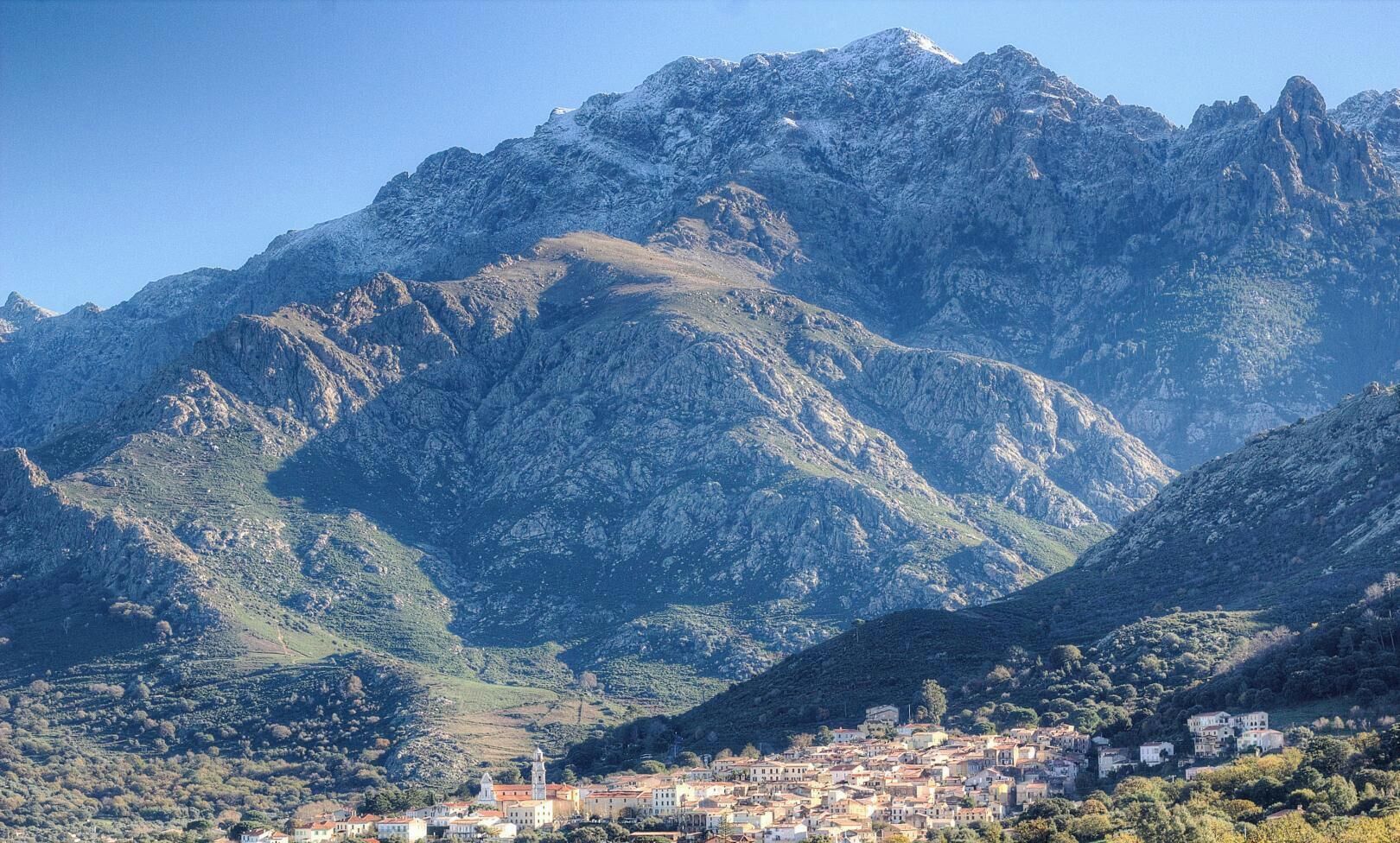 Paesaggio montuoso con una cittadina ai piedi.