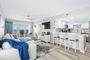 A modern living room with a sofa, coffee table, and a view of the outdoors. - Coastal Elegance | Renovated 4BR Oceanfront-Pool & Beach Access (North Myrtle Beach)