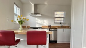 Una cocina moderna con encimera de madera, electrodomésticos de acero inoxidable y una silla roja.
