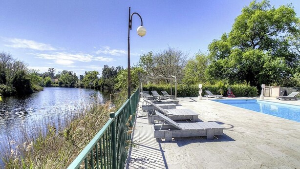 Zona de piscina con sillas de descanso, un puente y un farol.
