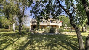A two-story building with a balcony, surrounded by trees and a well-maintained lawn. - Residence U Quarciu - GHISONACCIA (GHISONACCIA)