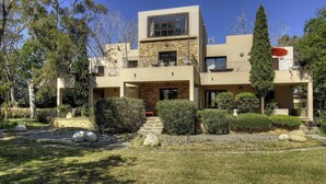 A modern two-story house with a stone facade, a balcony, and a well-maintained garden with rocks and shrubs. - Residence U Quarciu - GHISONACCIA (GHISONACCIA)