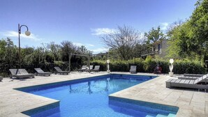 A rectangular swimming pool with a tiled deck, surrounded by lounge chairs and a pergola. - Residence U Quarciu - GHISONACCIA (GHISONACCIA)