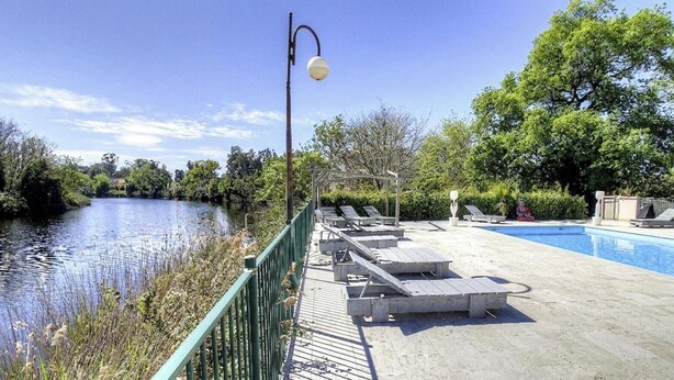 A pool area with lounge chairs, a bridge, and a lamp post. - Residence U Quarciu - GHISONACCIA (GHISONACCIA)