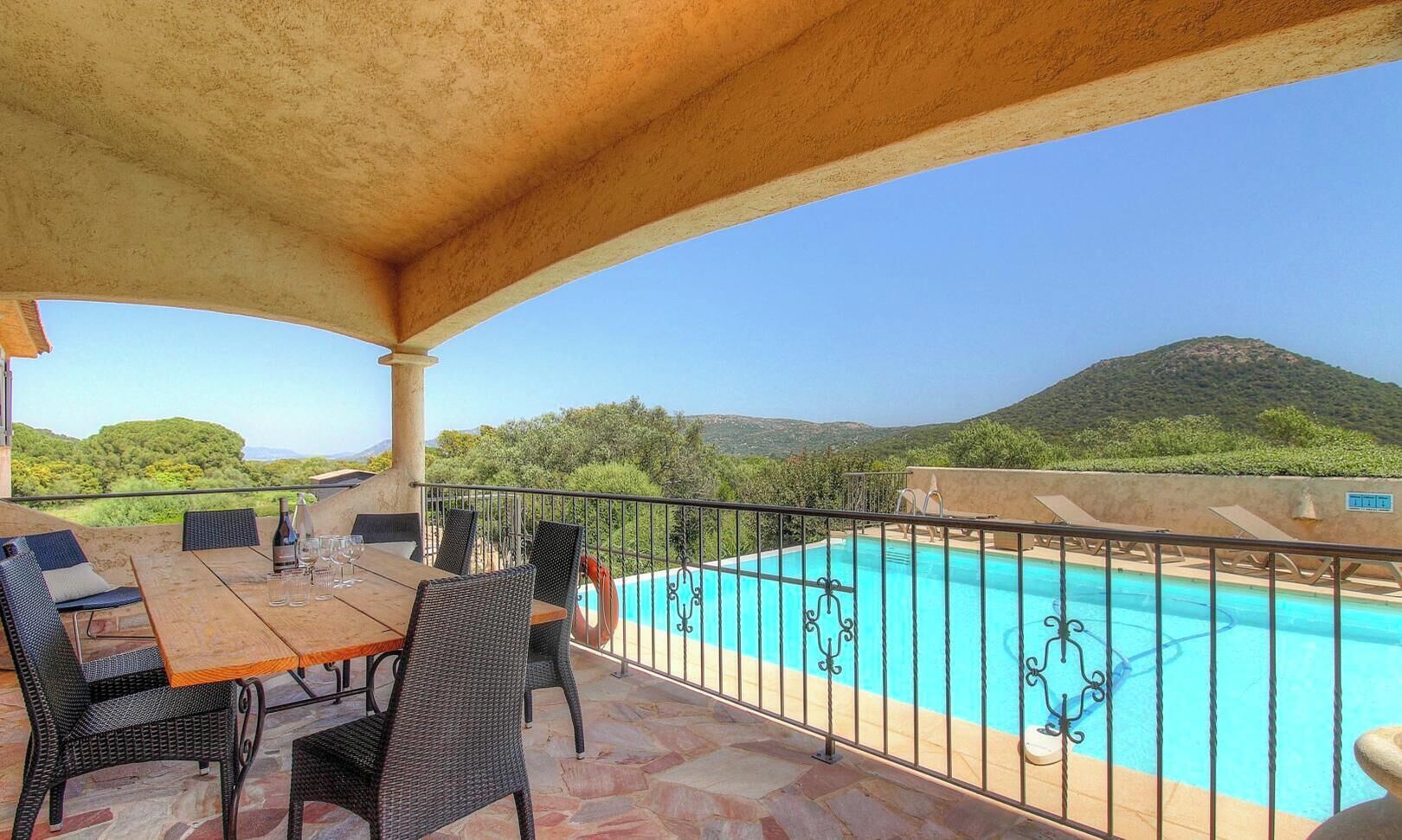 Un espace extérieur abrité comprenant une piscine, une table à manger et des chaises, avec vue sur un paysage montagneux.