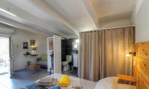 A bedroom with a bed, bedside table, and a view into the bathroom. - Petru-Pà - PORTO VECCHIO (PORTO VECCHIO)