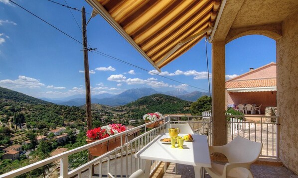 Ein Balkon mit Tisch, Stühlen und Blick auf eine Berglandschaft.