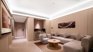 A modern living room with a sofa, a coffee table, and a kitchen area in the background. - Crystal Hotel Weihai Happiness Gate (Weihai)