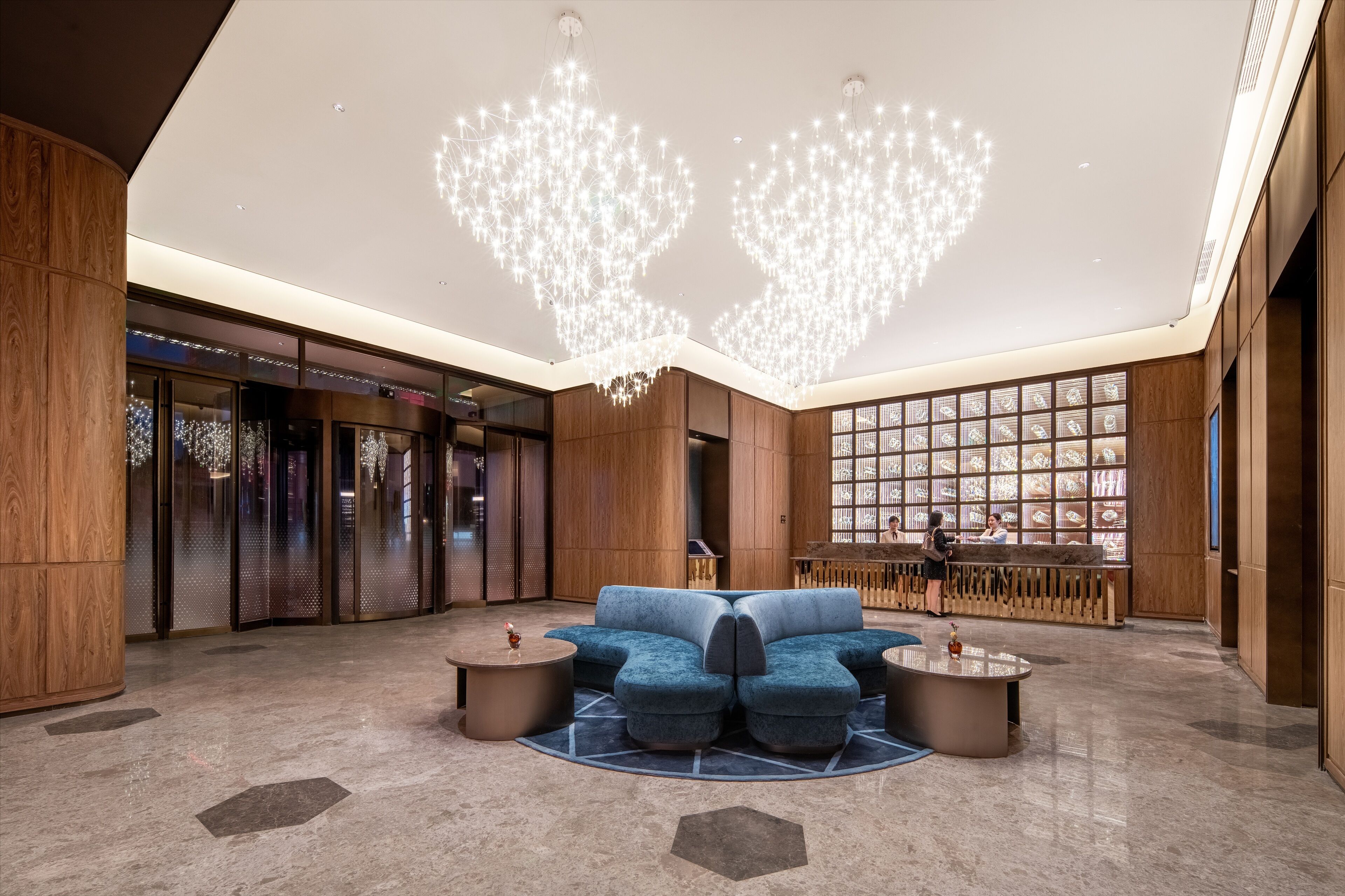 Eine moderne Lobby mit einem blauen Sofa, einem Chandelier und einem Empfangsschalter.