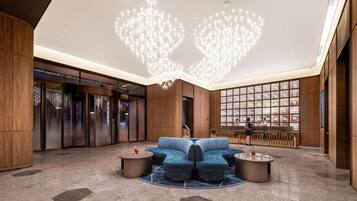 Eine moderne Lobby mit einem blauen Sofa, einem Chandelier und einem Empfangsschalter.