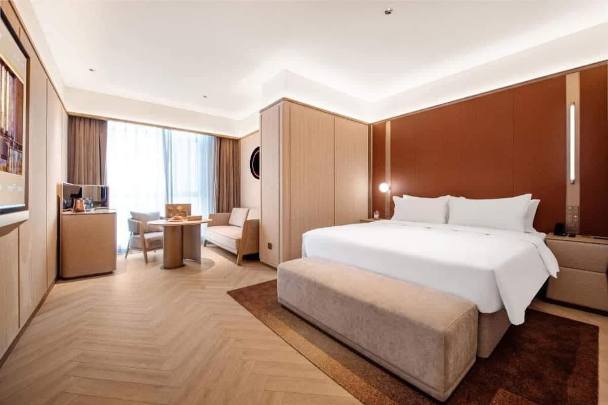 Hotellihuone, jossa on suuri sänky, työpöytä, tuoli ja sohva.