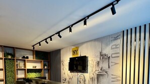 Una cocina moderna con barra, taburetes de bar, televisor montado en la pared y un mural con vista a la ciudad.