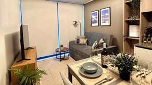Una sala moderna con sofá, comedor y televisor.