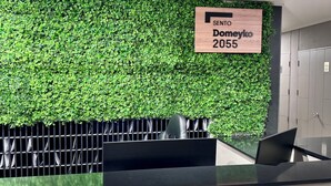 Una recepción con pared verde y un letrero que indica 'SENTO Doneyko 2055'.