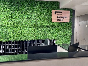 Ein Empfangsschalter mit grüner Wand und einem Schild mit der Aufschrift 'SENTO Doneyko 2055'.