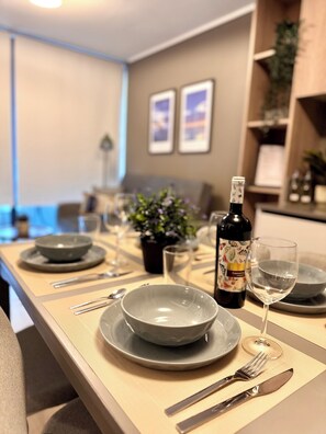 Mesa de jantar posta com pratos, talheres, garrafa de vinho e copos.