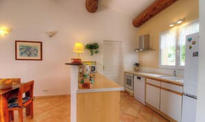 A compact kitchen with a wooden island, white cabinets, a microwave, oven, and a refrigerator. - L'abri côtier - SAGONE - Gîte (SAGONE)