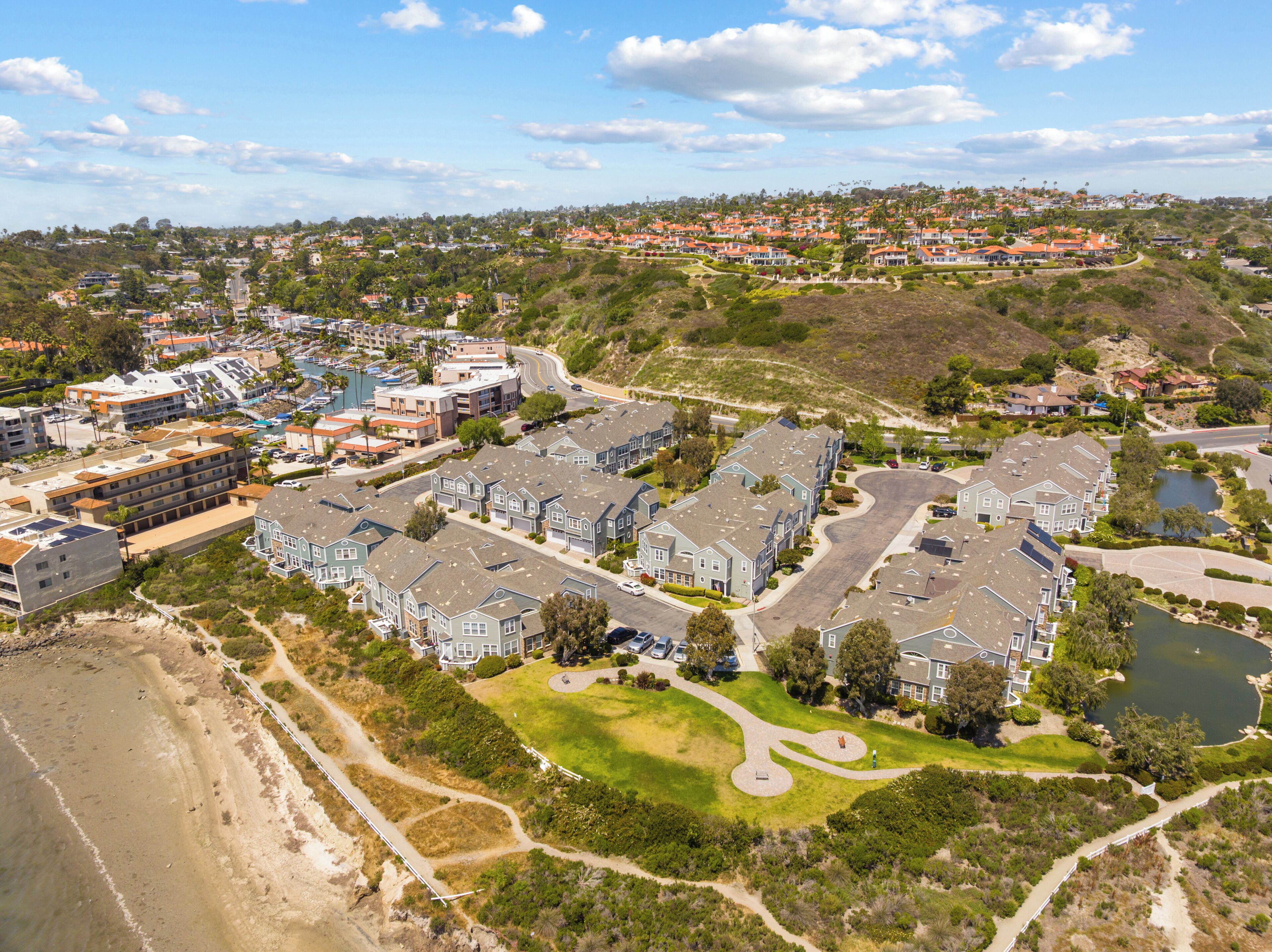 A residential area with multiple-story houses, a beach, and a small lake.