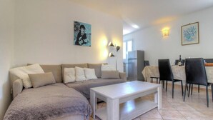 Uma sala de estar com sofá, mesa de centro, mesa de jantar e cadeiras, e obras de arte nas paredes.
