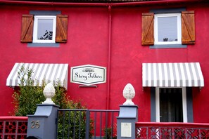 A red building with a sign reading 'Story Tellers' and a number '25' on the gate. - Condessa Novo - Storytellers Boutique Villas (São Pedro)