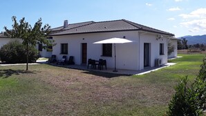 Une maison de plain-pied dotée d’un patio, d’un espace salon extérieur et offrant une vue sur le paysage environnant.